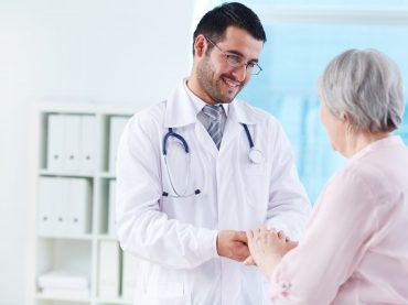 Confident doctor looking at his senior patient while speaking to her